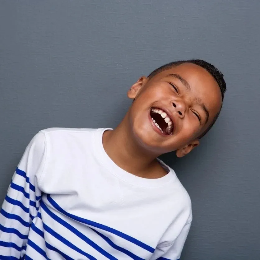 A young boy laughing with his mouth open.